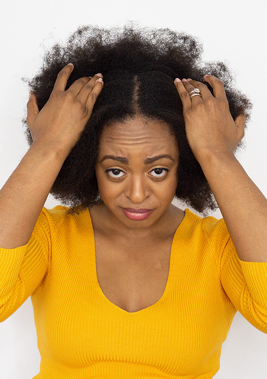 frowning woman with big afro wearing yellow v neck