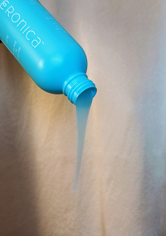 sky blue bottle turned upside down with shampoo pouring out.